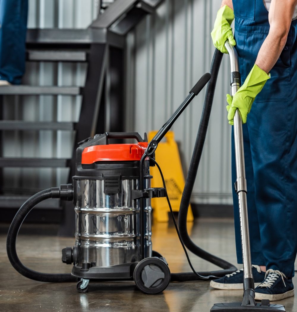 cropped view of cleaner in uniform cleaning floor with vacuum cleaner cropped view of cleaner in uniform cleaning floor with vacuum cleaner